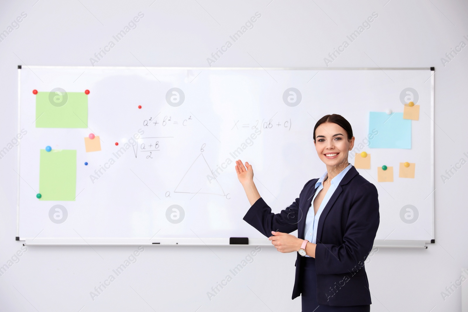 Photo of Young teacher near whiteboard in modern classroom. Space for text