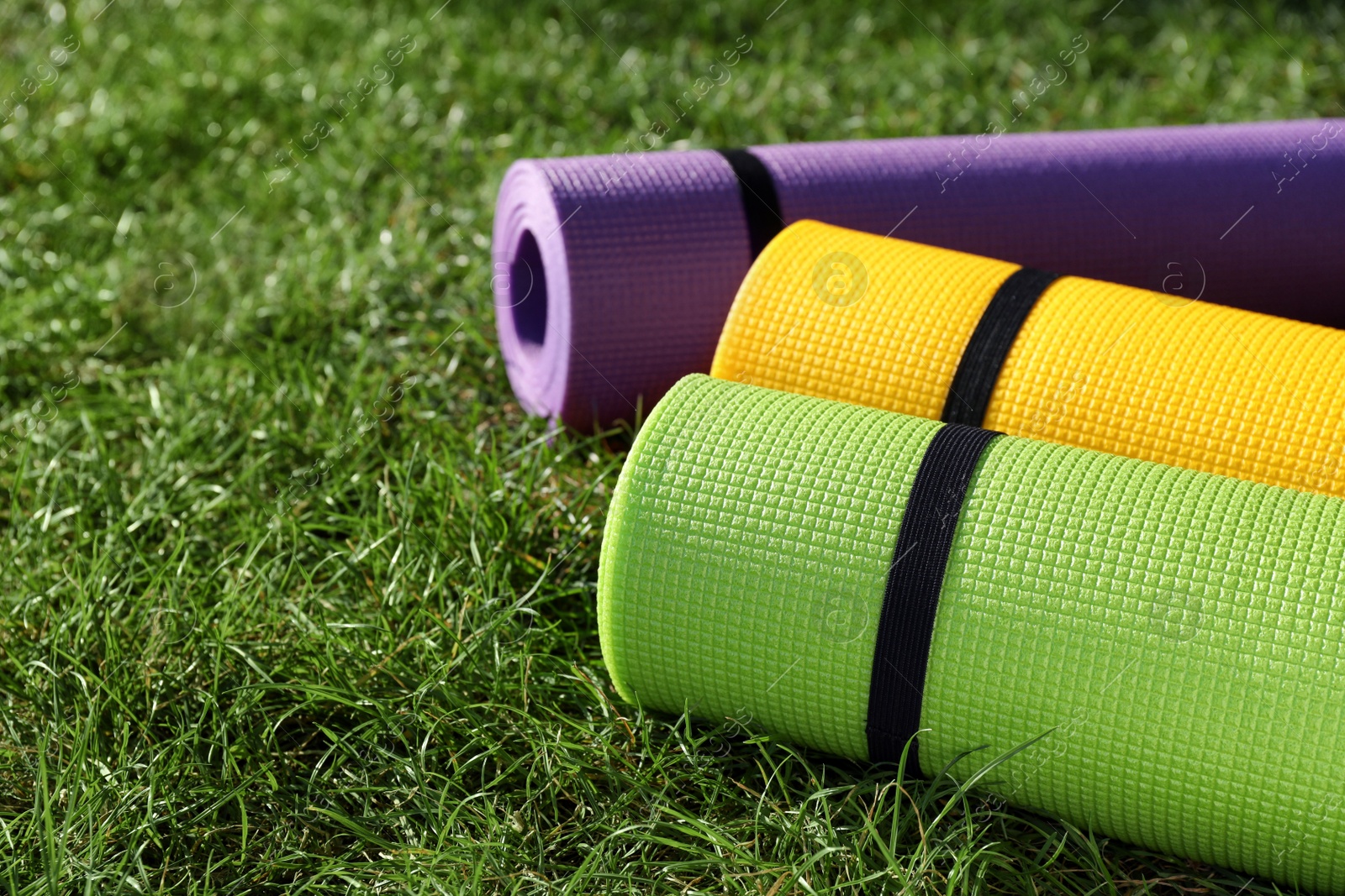 Photo of Bright exercise mats on fresh green grass outdoors, closeup