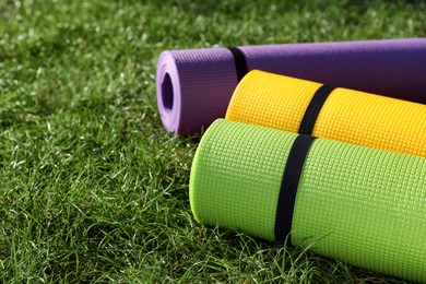 Photo of Bright exercise mats on fresh green grass outdoors, closeup