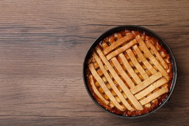 Photo of Delicious apricot pie in baking dish on wooden table, top view. Space for text