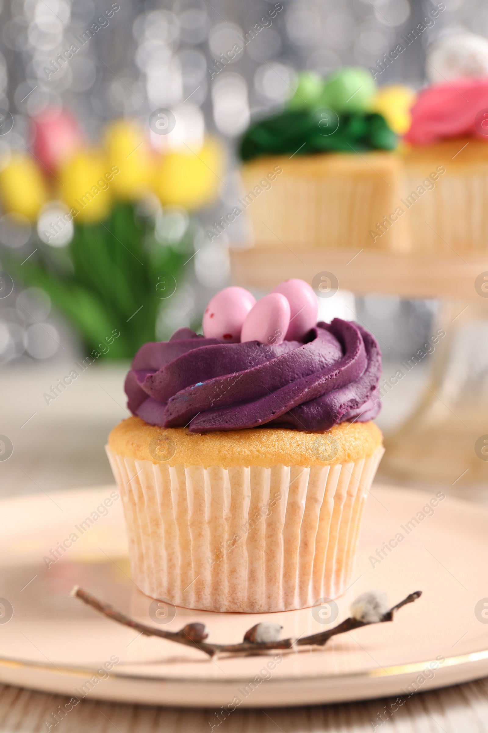 Photo of Tasty Easter cupcake and willow branch on table, closeup