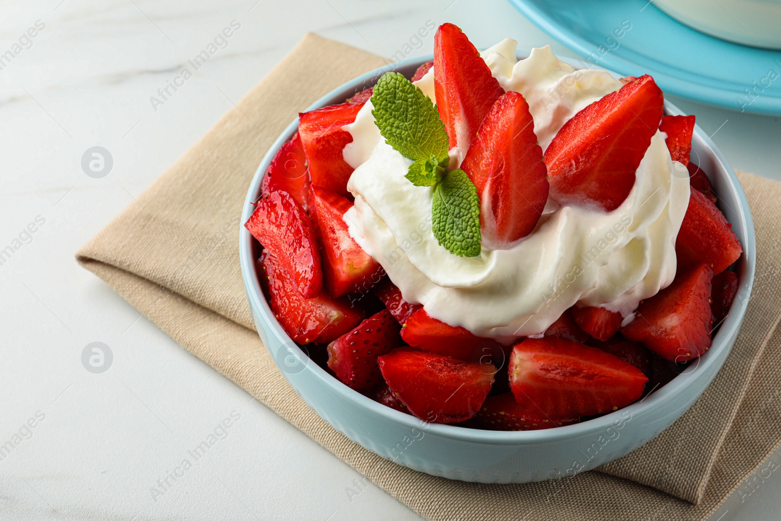 Photo of Delicious strawberries with whipped cream served on white table, closeup