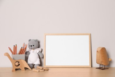 Photo of Empty square frame, stationery and different toys on wooden table