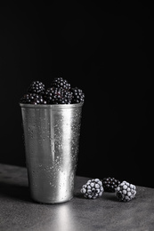 Photo of Fresh and frozen blackberries on grey table against dark background