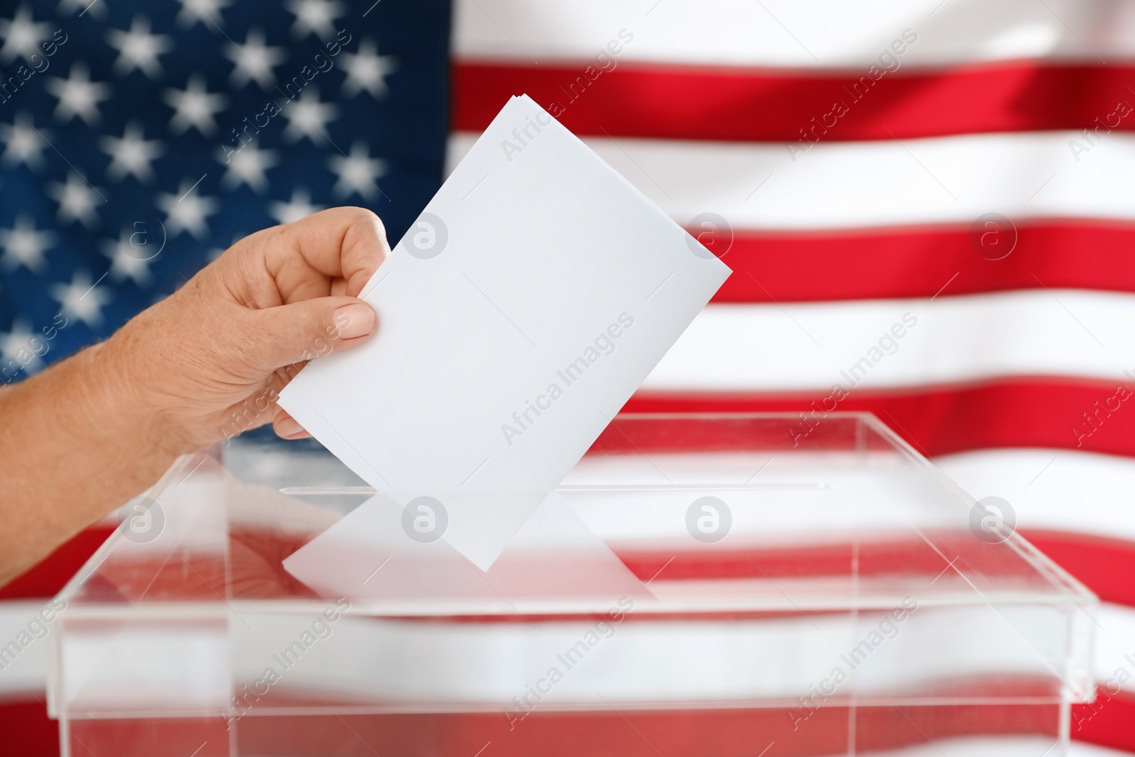 Photo of Elderly woman putting ballot paper into box and American flag on background, closeup