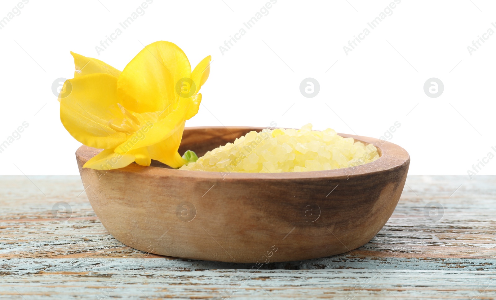Photo of Natural sea salt in bowl and flower on wooden table against white background