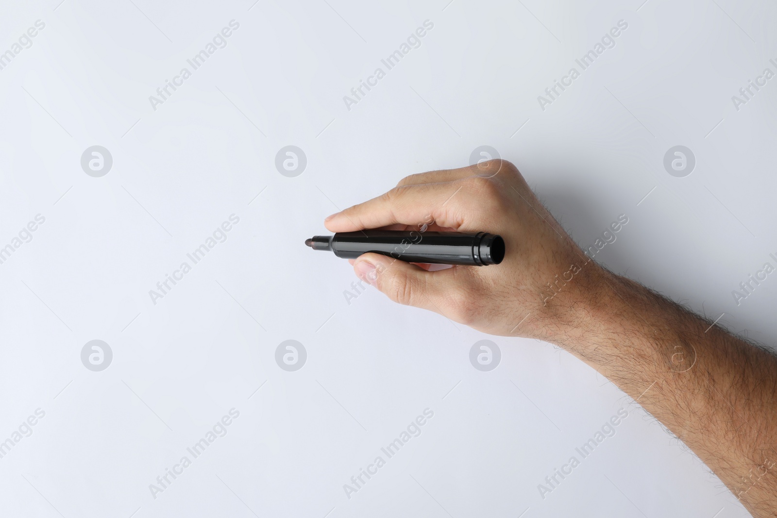 Photo of Man holding black marker on white background, top view