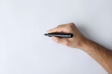 Man holding black marker on white background, top view