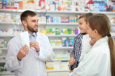 Image of Professional pharmacist working with customer in modern drugstore