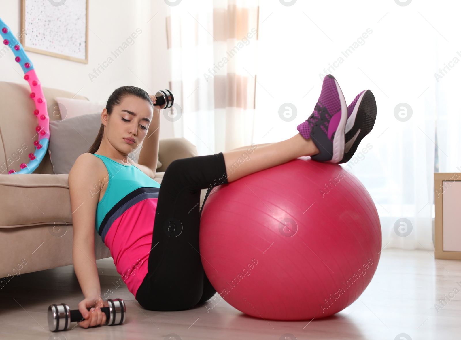 Photo of Lazy young woman with sport equipment at home