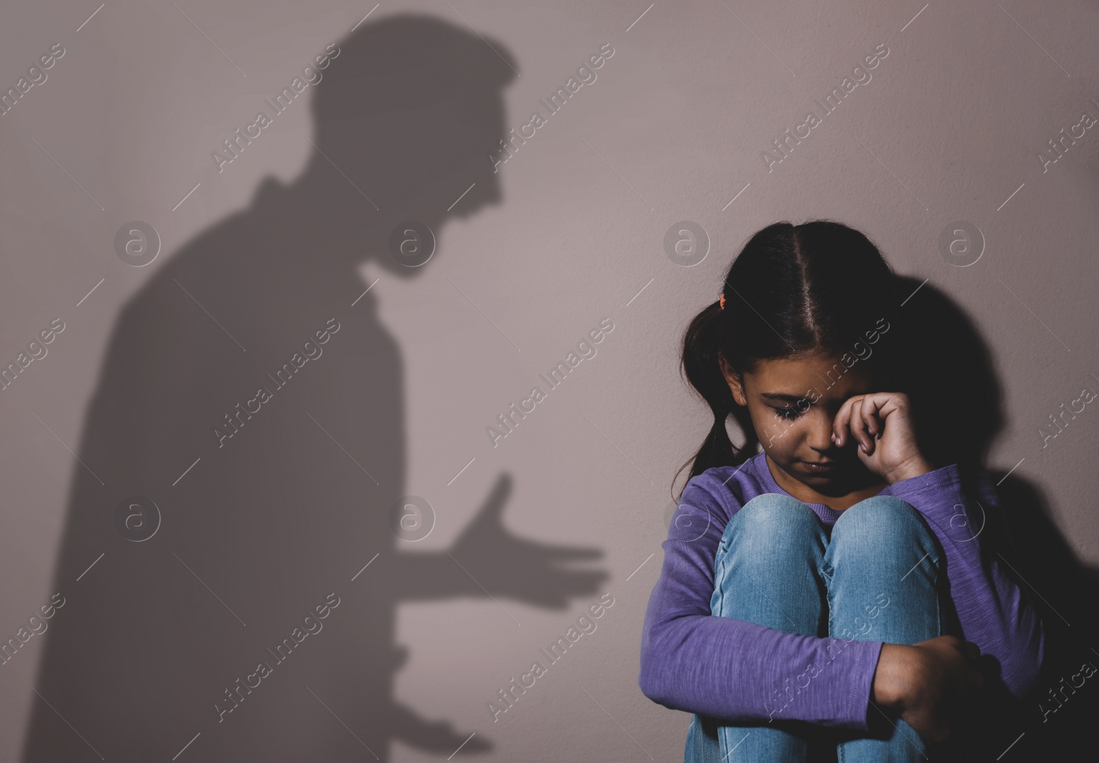 Image of Child abuse. Father yelling at his daughter. Shadow of man on wall