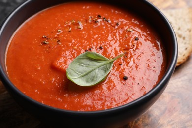 Photo of Delicious tomato cream soup in bowl on wooden table, closeup