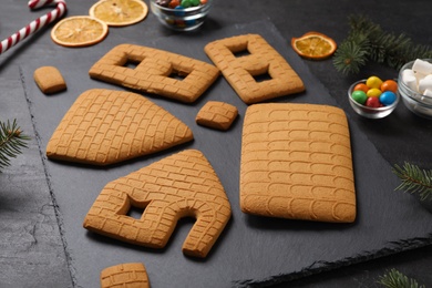 Photo of Parts of gingerbread house on black table, closeup