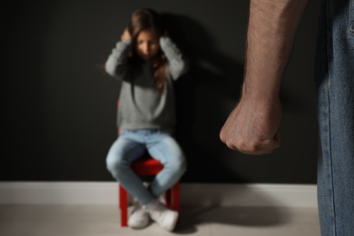 Photo of Man threatening his daughter indoors, closeup. Domestic violence concept