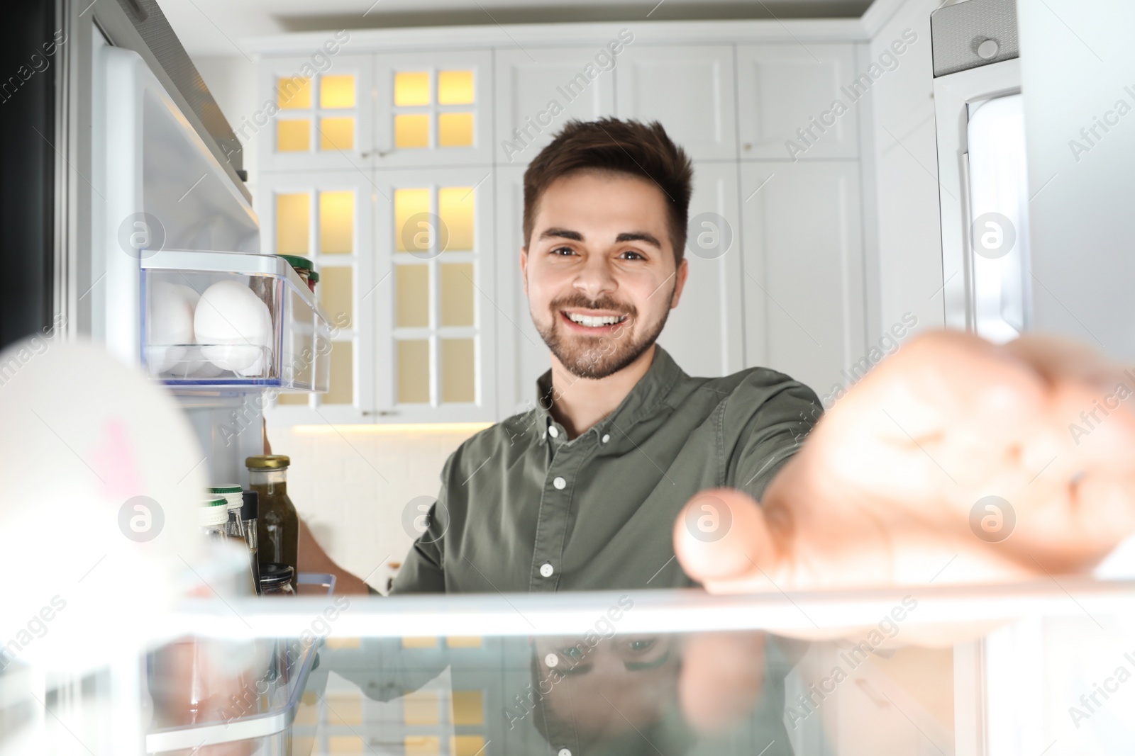 Photo of Young man looking into refrigerator, view from inside