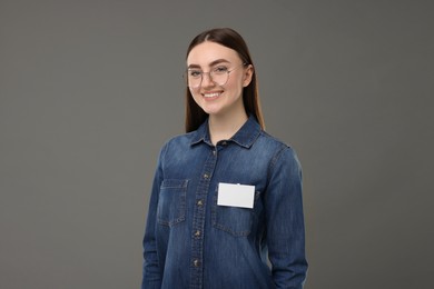 Happy woman with blank badge on grey background