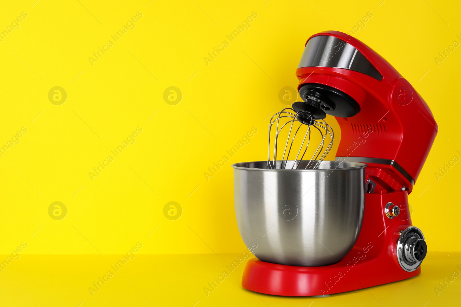 Photo of Modern red stand mixer on yellow background, space for text