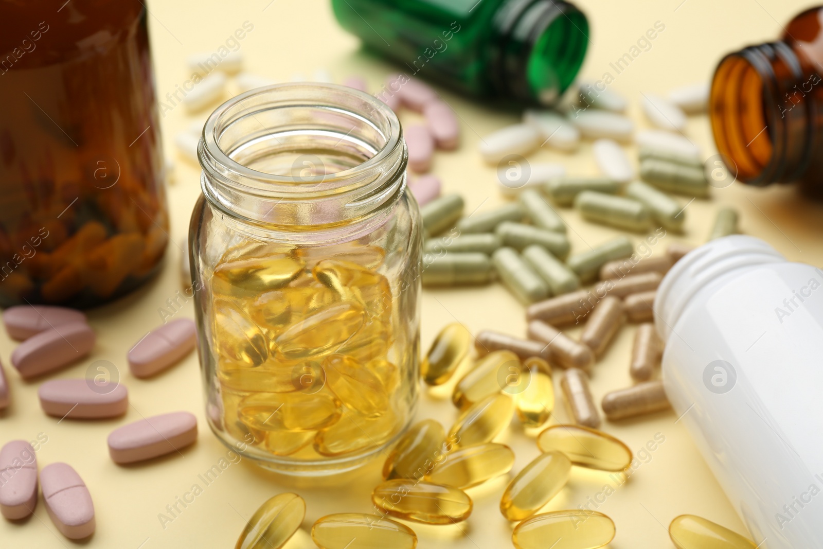 Photo of Many different vitamin pills and bottles on beige background, closeup