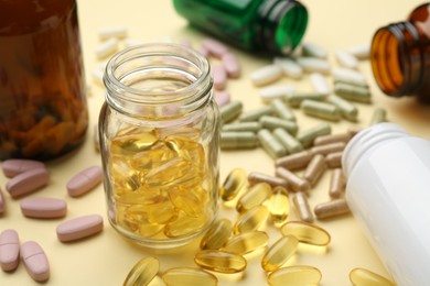 Photo of Many different vitamin pills and bottles on beige background, closeup