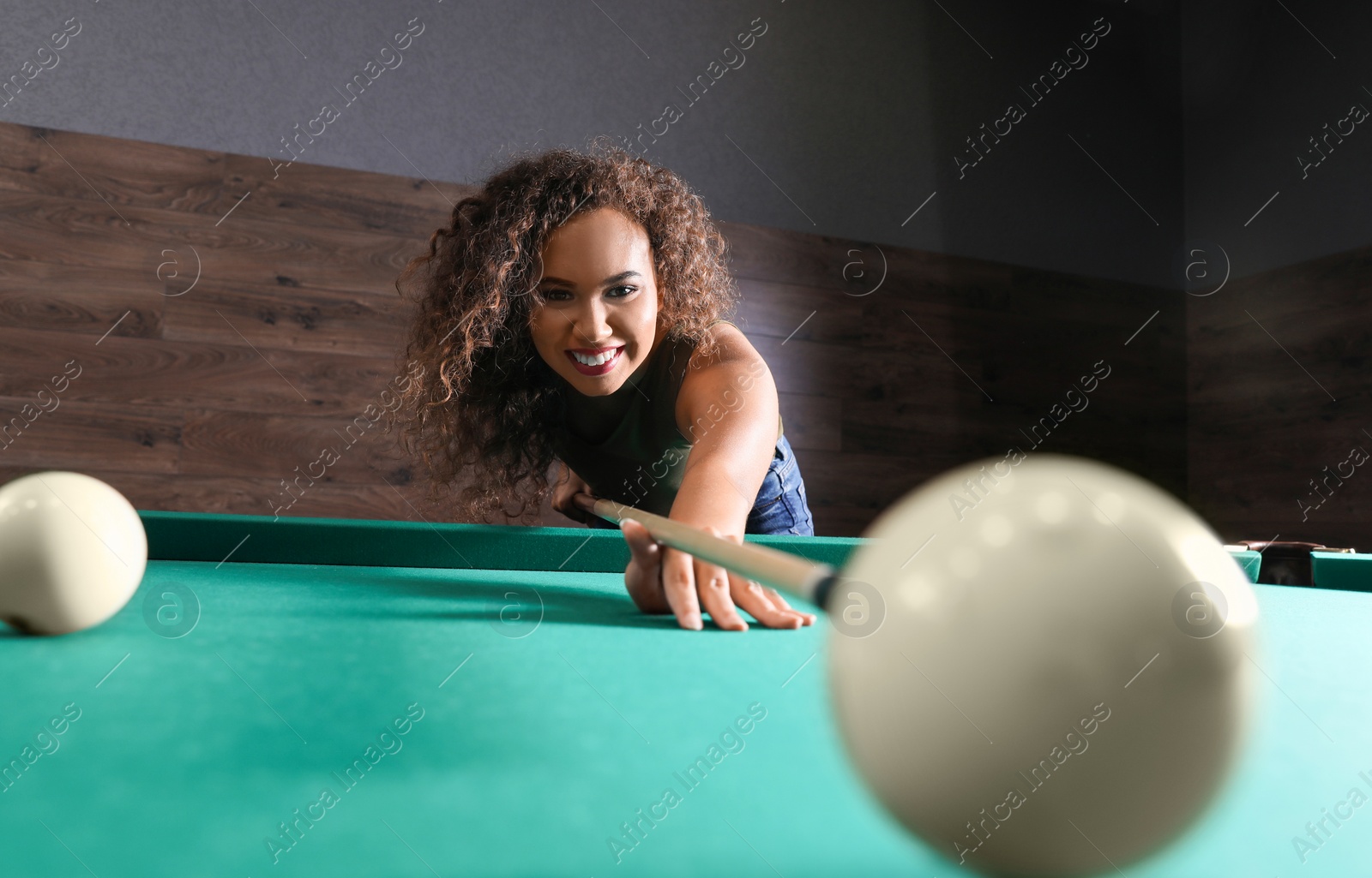 Photo of Young African-American woman playing Russian billiard indoors