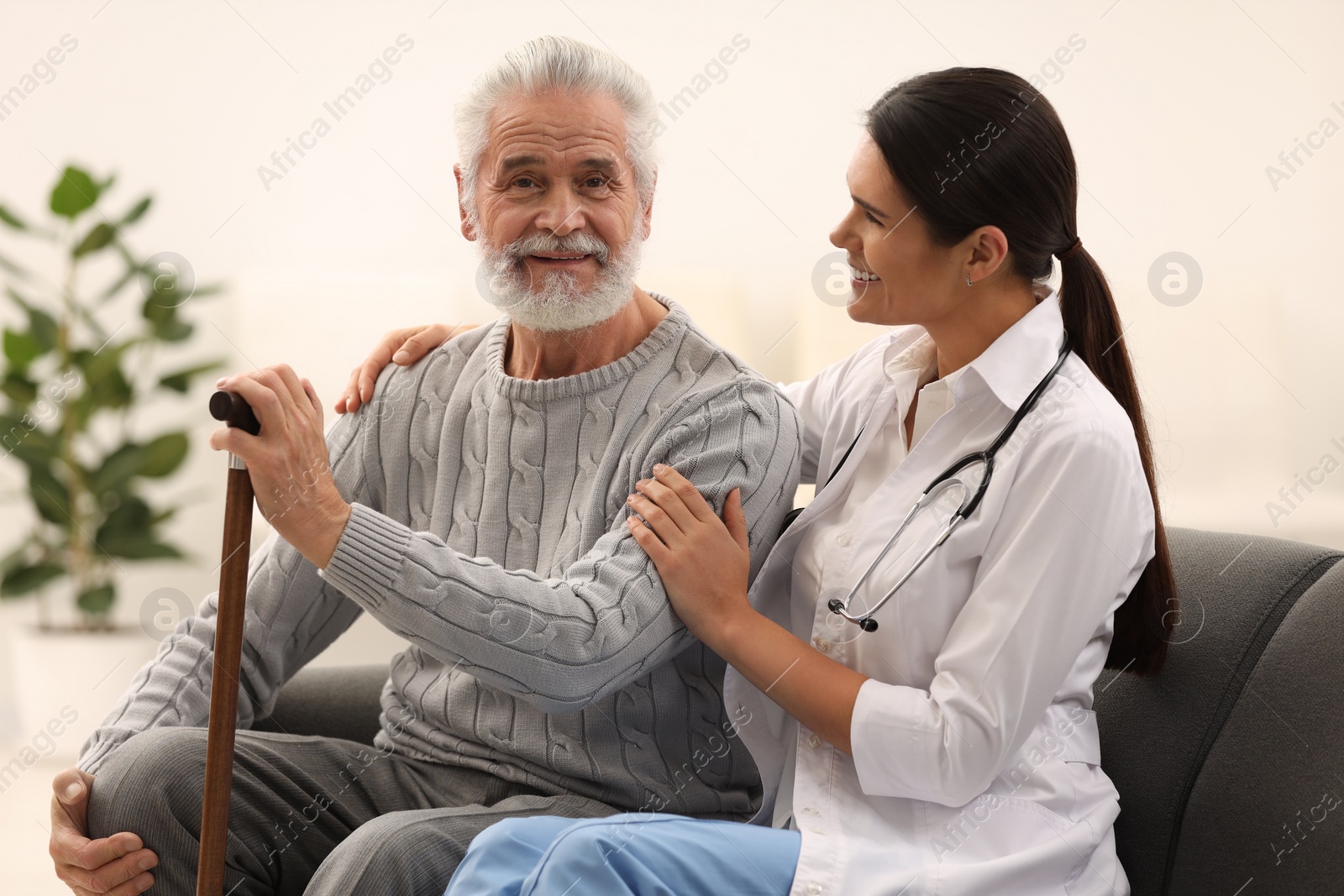 Photo of Smiling nurse supporting elderly patient in hospital