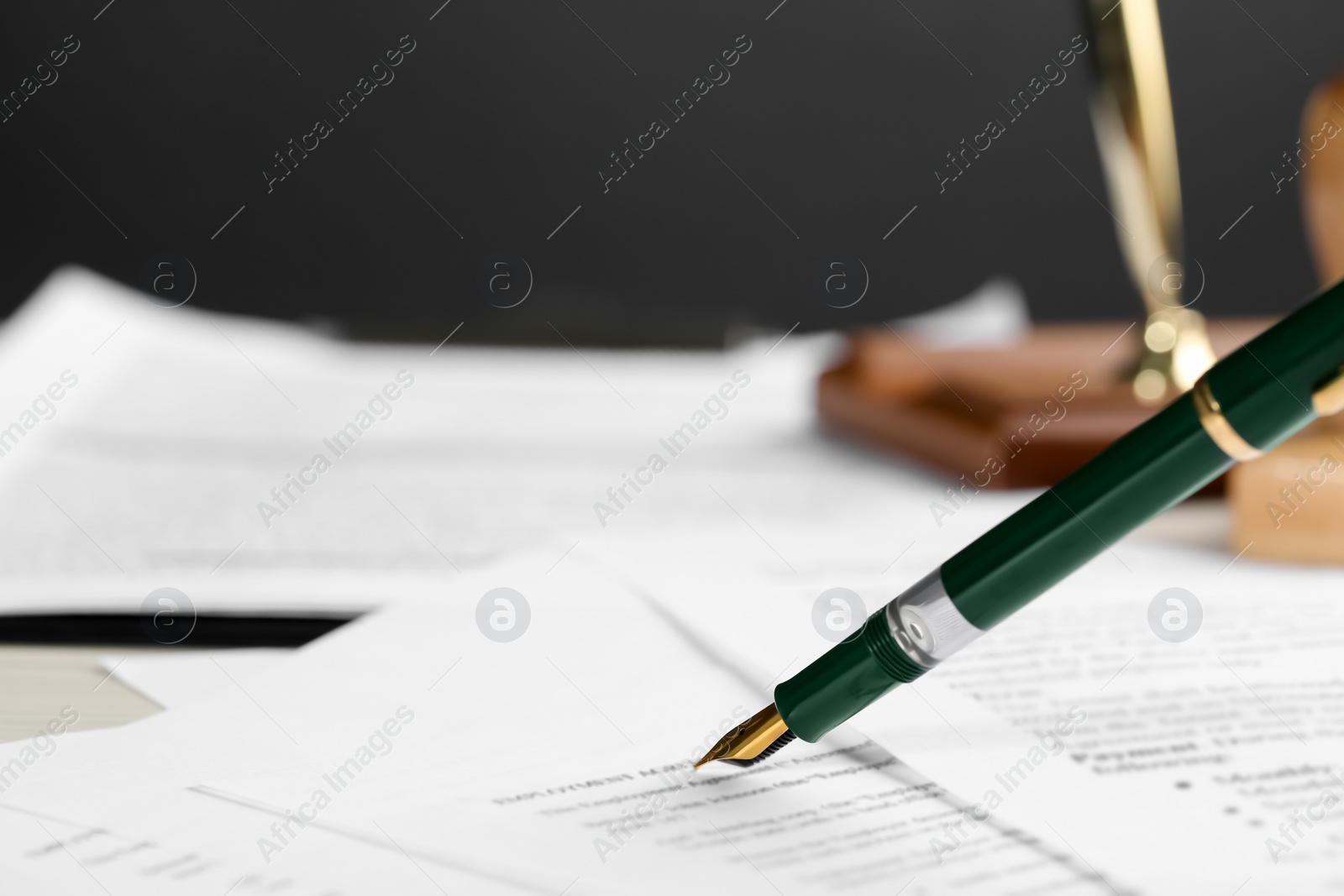 Photo of Signing notary document with fountain pen at light table, closeup. Space for text