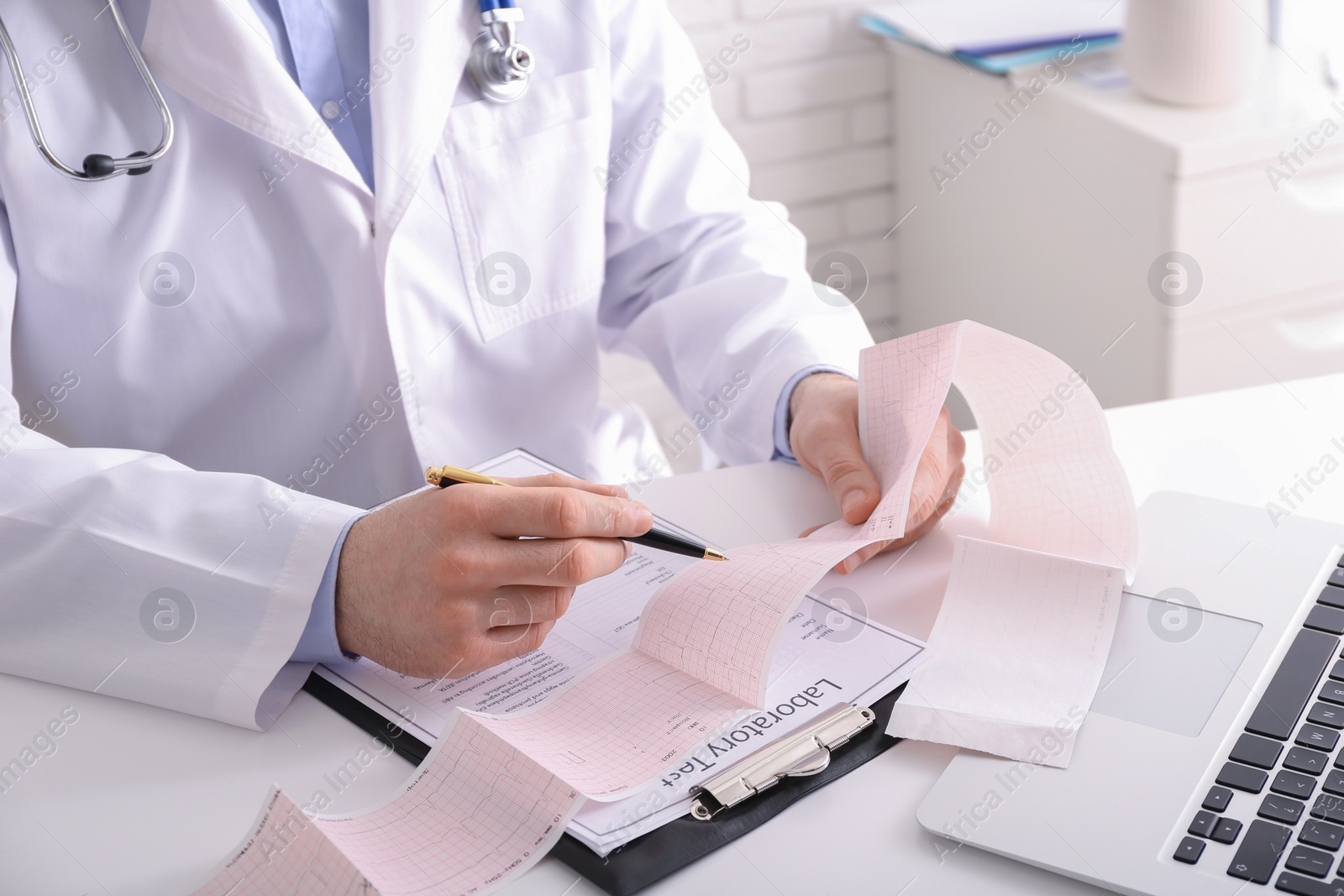 Photo of Doctor examining cardiogram at table in clinic, closeup