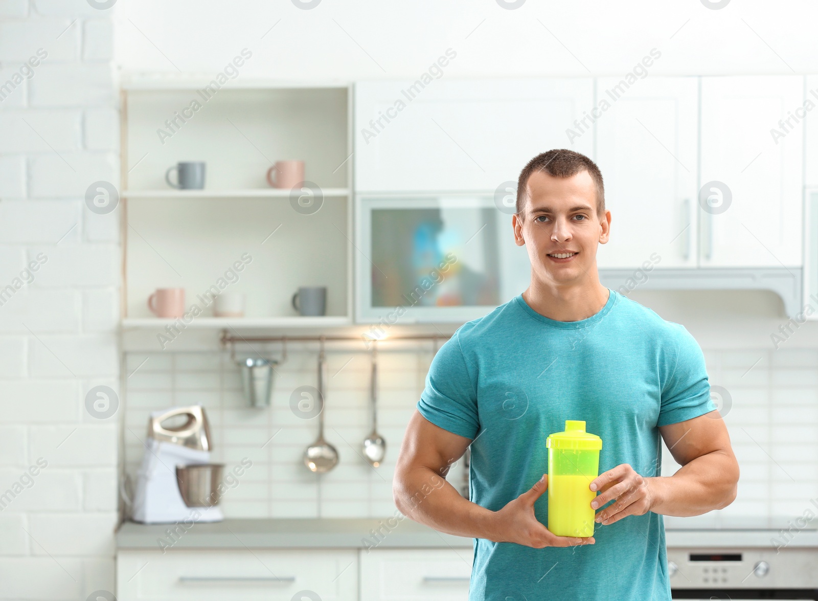 Photo of Athletic young man with protein shake in kitchen