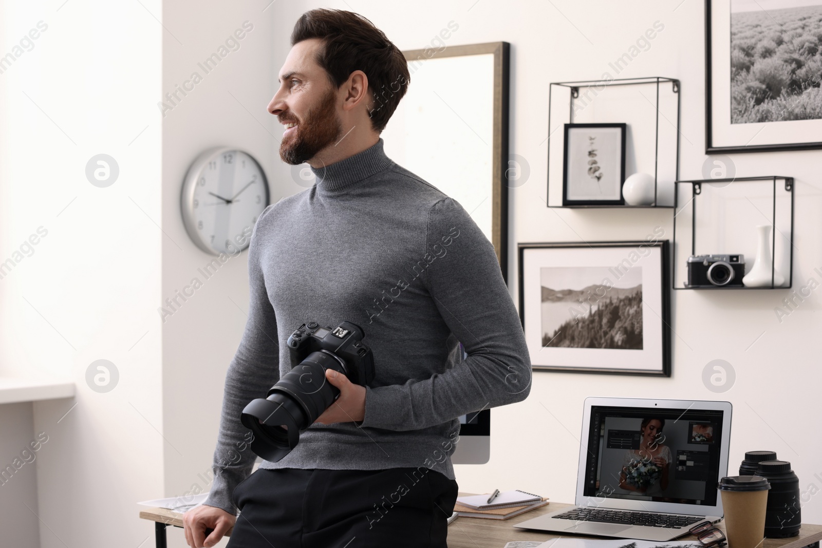 Photo of Professional photographer with digital camera near table in office