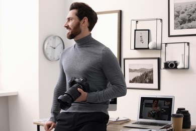 Photo of Professional photographer with digital camera near table in office