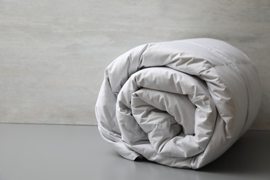 Photo of Soft rolled blanket on light grey table, closeup