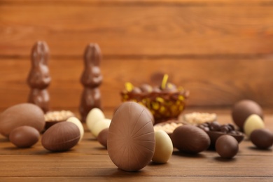 Photo of Sweet chocolate eggs on wooden table. Space for text