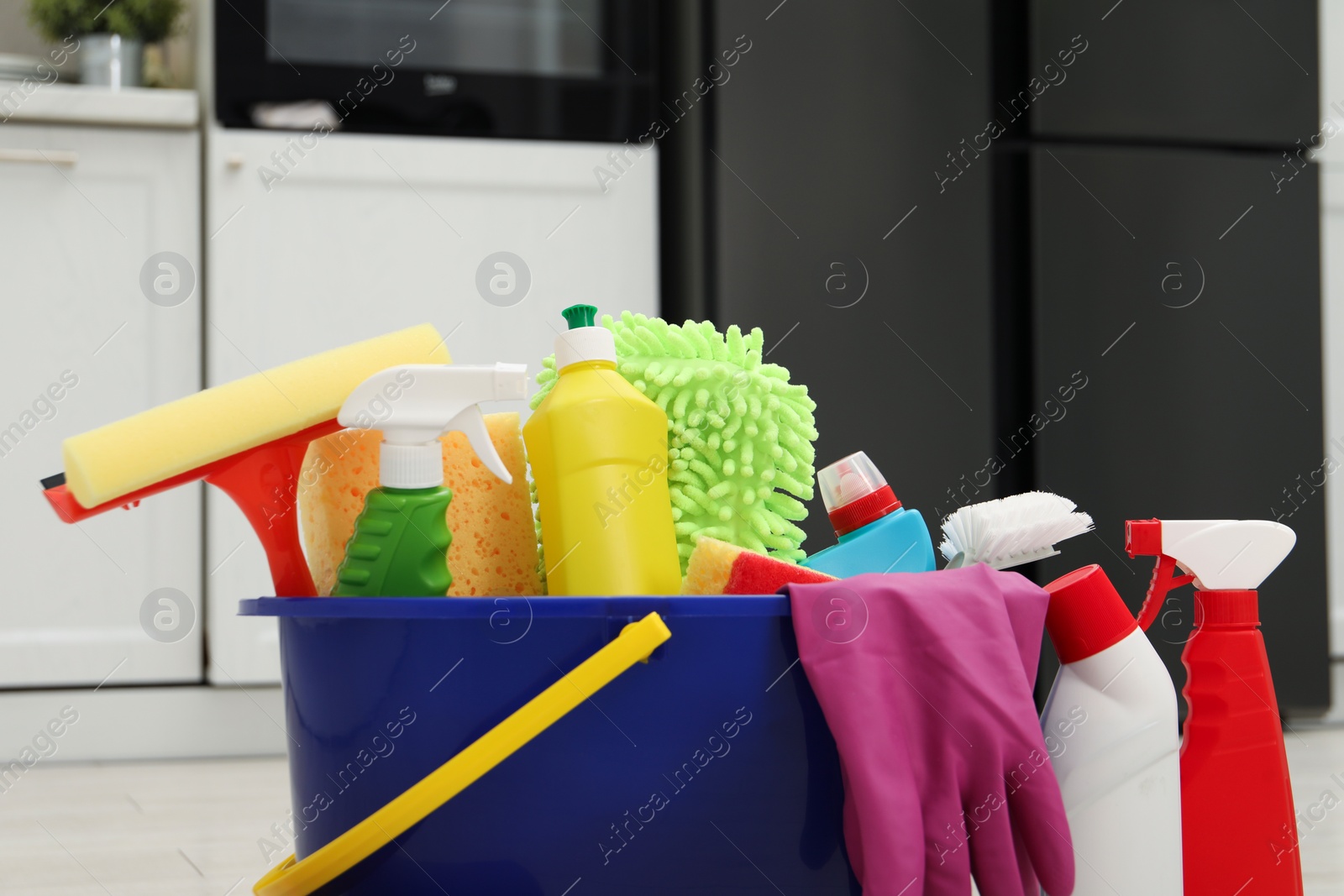 Photo of Different cleaning supplies in bucket indoors, closeup