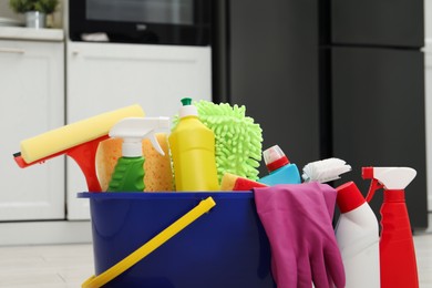 Photo of Different cleaning supplies in bucket indoors, closeup