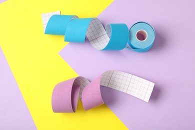 Photo of Bright kinesio tape in rolls on color background, flat lay