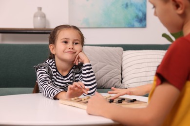 Photo of Children playing checkers at coffee table in room