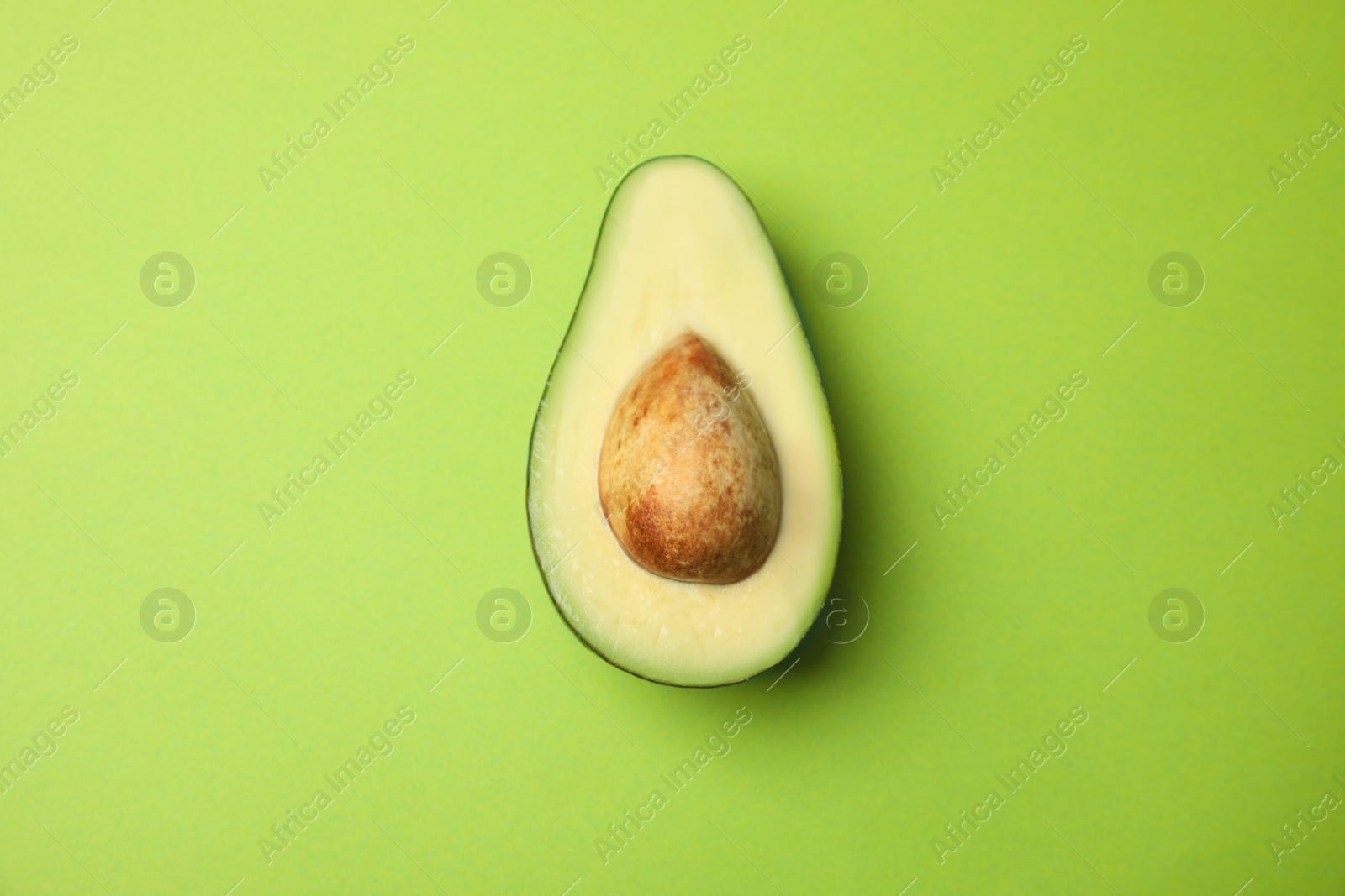 Photo of Cut fresh ripe avocado on green background, top view