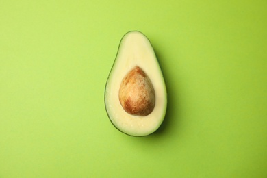 Cut fresh ripe avocado on green background, top view