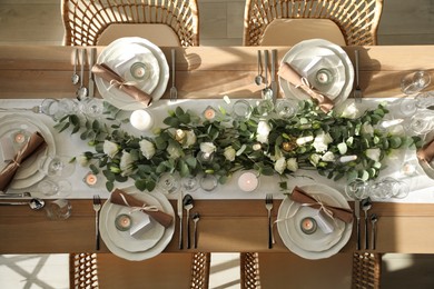 Photo of Elegant table setting with beautiful floral decor and burning candles, top view