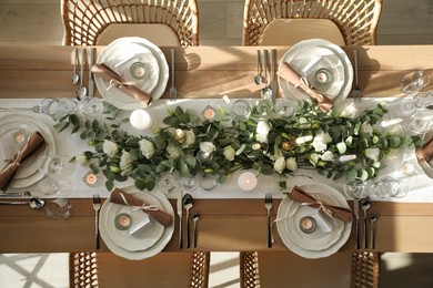 Elegant table setting with beautiful floral decor and burning candles, top view