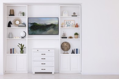 Photo of Interior design. Stylish tv area, chest of drawers and shelves with accessories indoors. Space for text