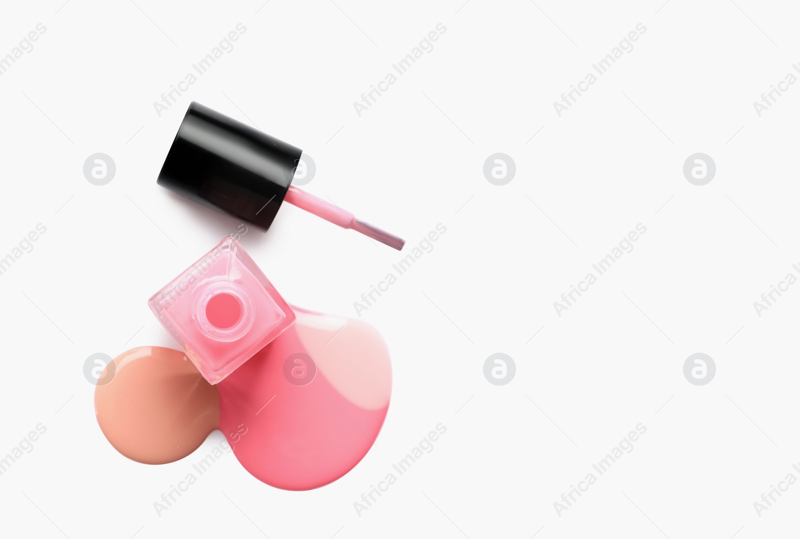 Photo of Spilled different nail polishes with bottle and brush on white background, top view