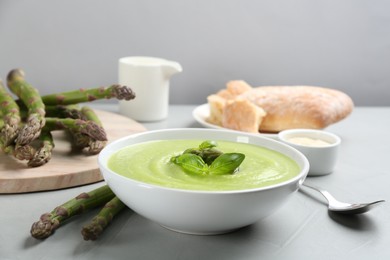 Photo of Delicious asparagus soup served on grey table