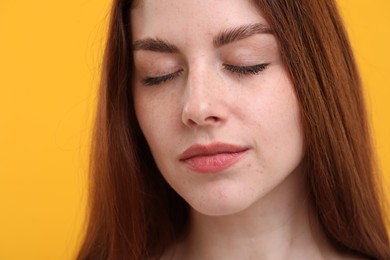 Photo of Portrait of beautiful woman with freckles on yellow background, closeup