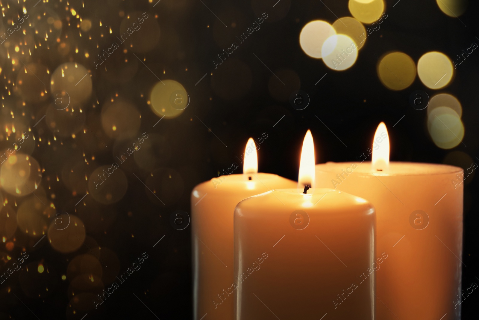 Image of Wax candles burning on black background with blurred lights, closeup. Bokeh effect
