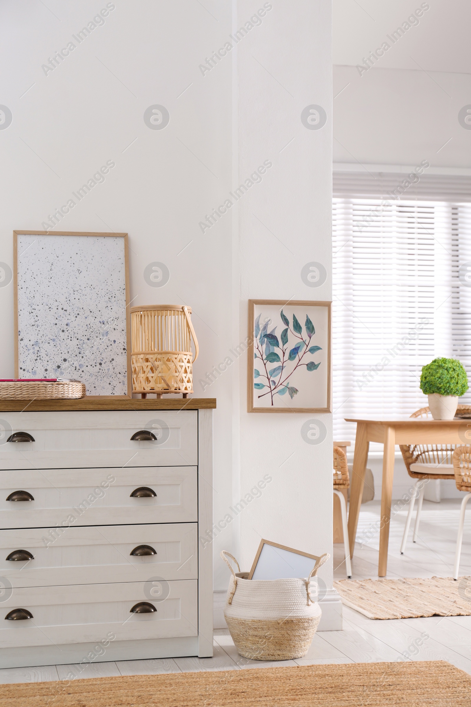 Photo of Stylish wicker holder with candle on chest of drawers indoors