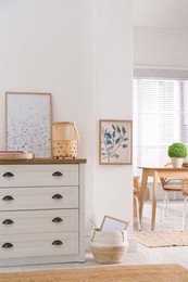 Photo of Stylish wicker holder with candle on chest of drawers indoors