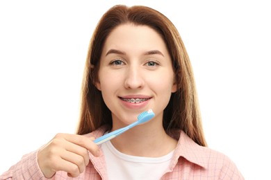 Photo of Smiling woman with dental braces cleaning teeth on white background