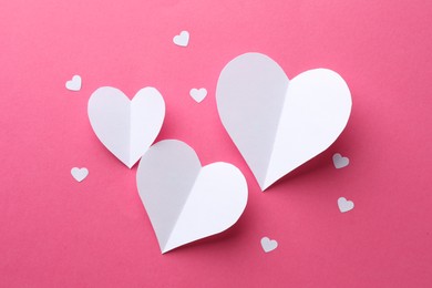 White paper hearts on pink background, flat lay