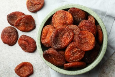 Bowl of tasty apricots on grey table, flat lay. Dried fruits